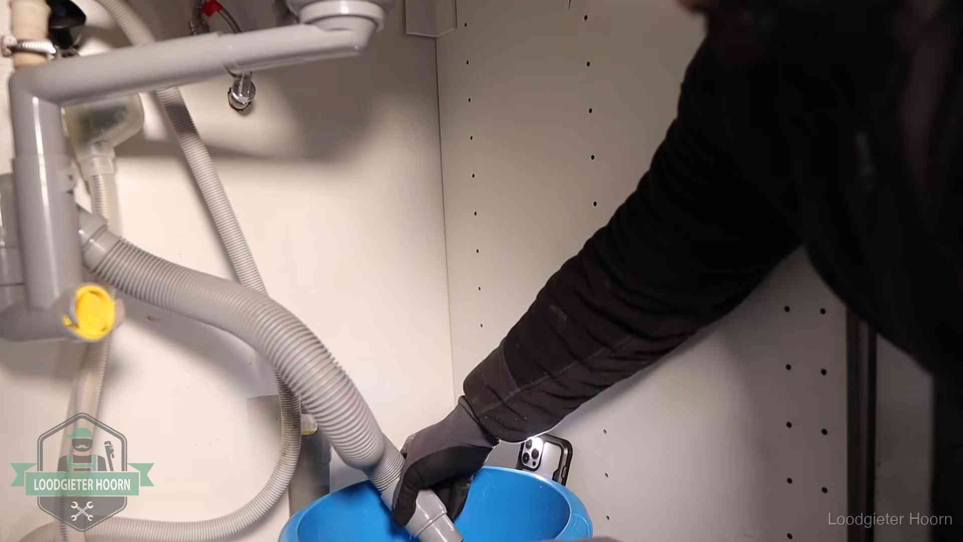 Afvoerslang loopt leeg in een emmer onder de gootsteen in Hoorn, een klus die je zelf kunt doen