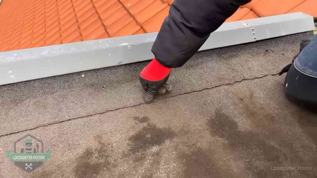 Lekkage bij de naad van een plat dak in Hoorn Vakman wijst een naad met vochtplekken aan op een bitumen plat dak in Hoorn