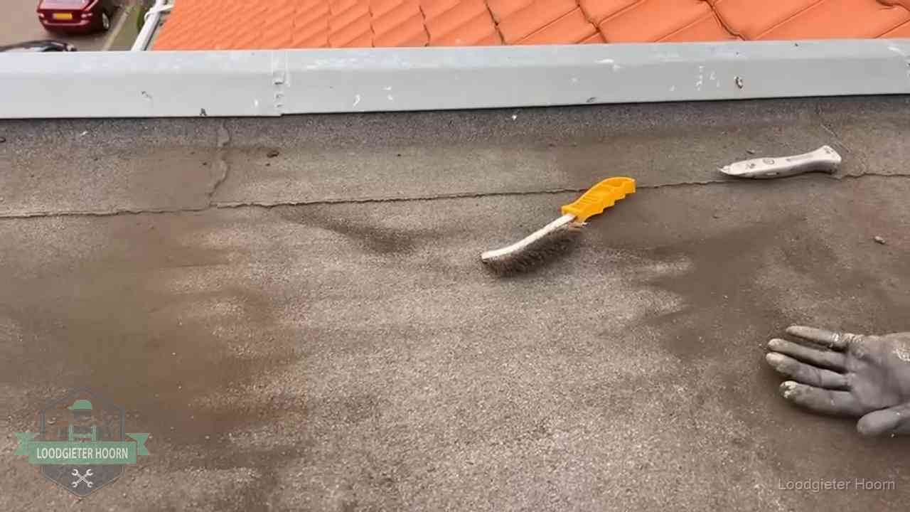 Kosten van daklekkage-reparatie in Hoorn Dakdekker bereidt een bitumen plat dak voor op reparatie bij de daktrim in Hoorn