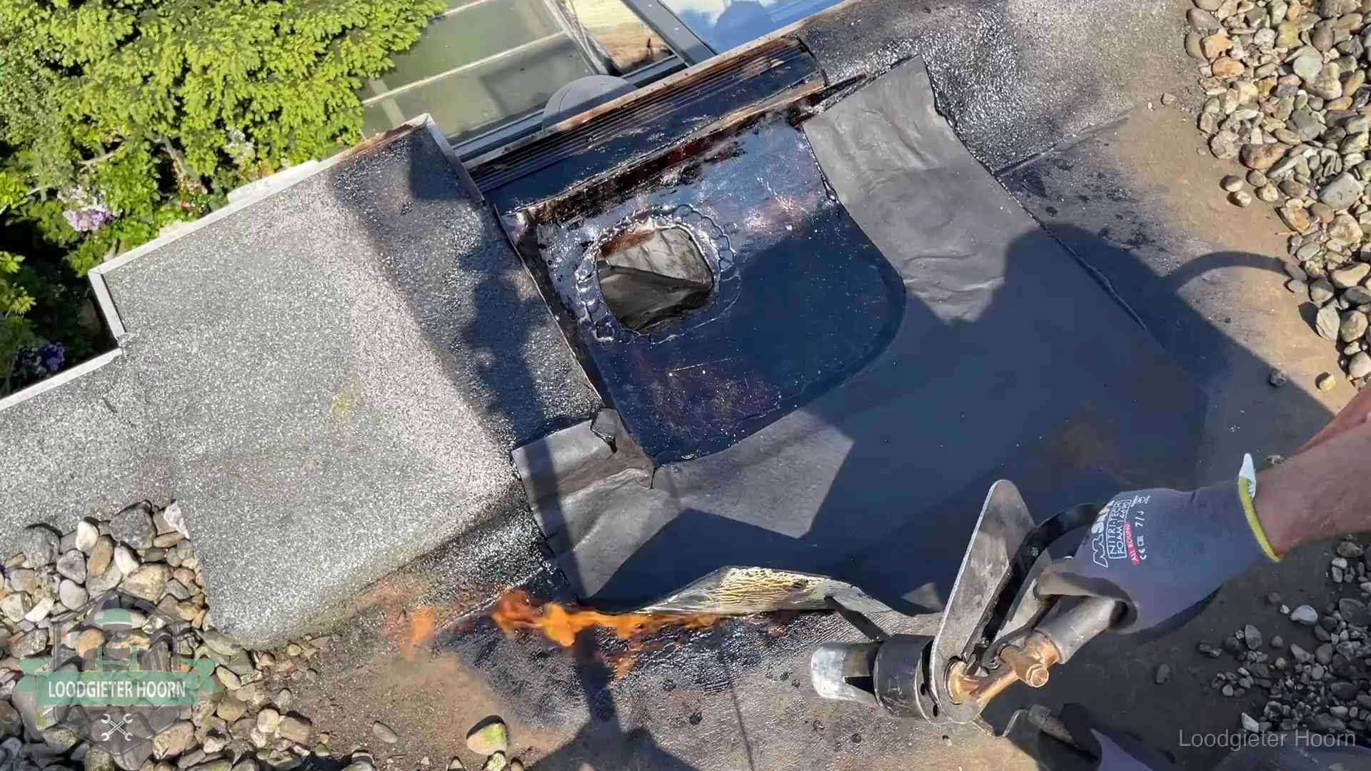 Daklekkage repareren in Hoorn Dakdekker brandt bitumen rond een doorvoer tijdens een daklekkage-reparatie in Hoorn