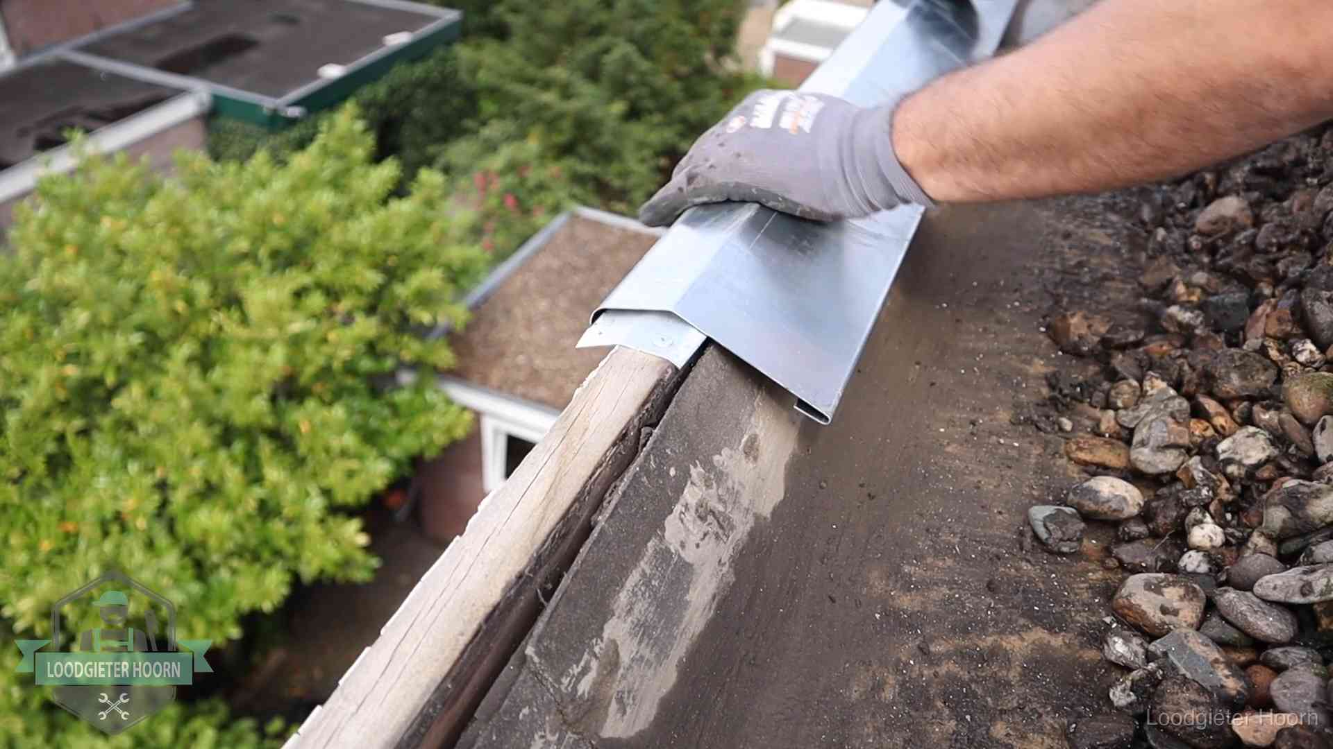 Daklekkage per wijk in Hoorn Dakdekker plaatst een zinken deklijst op een dakrand met uitzicht over een woonwijk in Hoorn