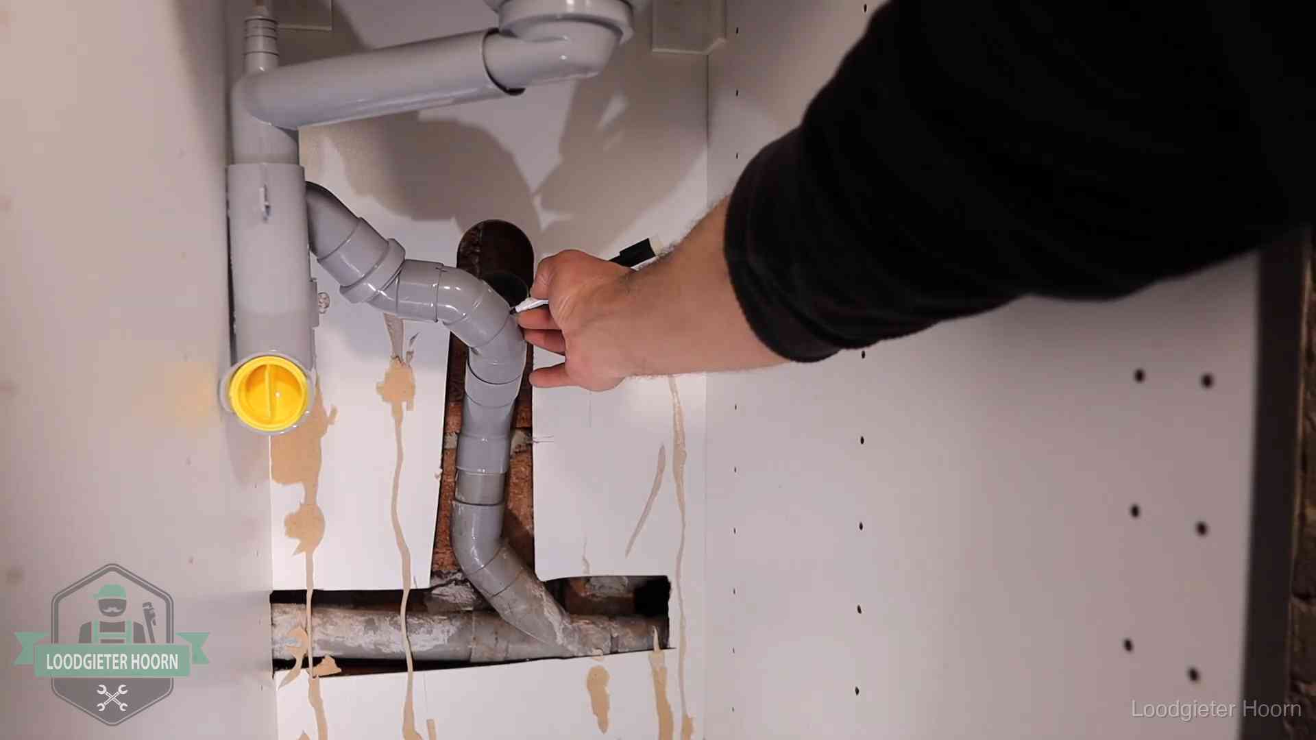Loodgieter voor verhuurders en bedrijven in Hoorn Loodgieter markeert een pvc-afvoerbuis onder een gootsteen in Hoorn