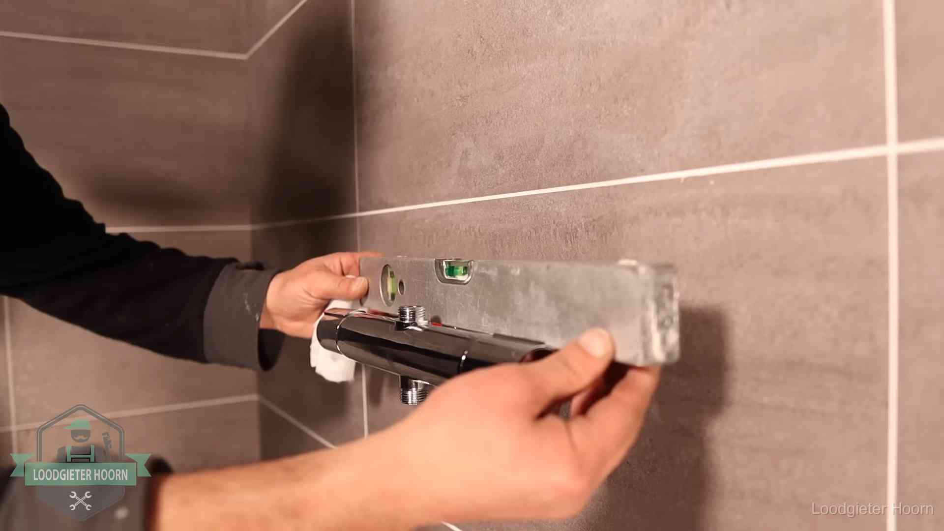 Loodgietersbedrijf voor sanitair in Hoorn Loodgieter lijnt een douchekraan uit met een waterpas in een woning in Hoorn