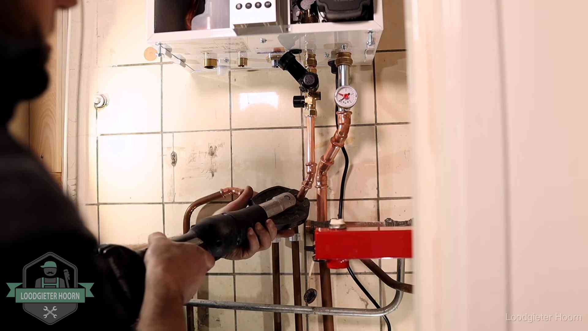 Monteur werkt aan de leidingen onder een cv-ketel in Hoorn
