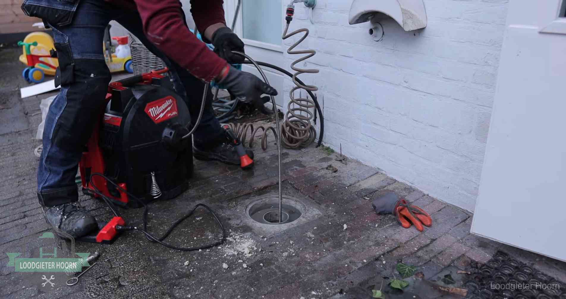 Ontstoppingsputje in de bestrating naast de gevel van een woning in Hoorn