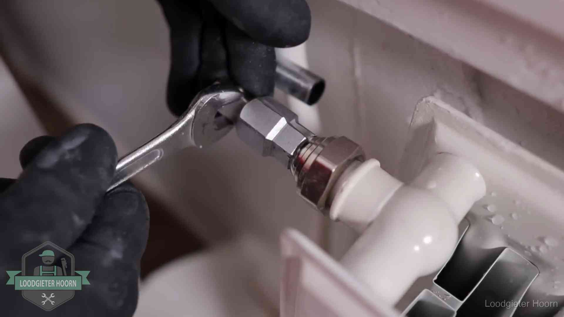 Steeksleutel draait een wartelkoppeling op een radiatorkraan aan in Hoorn