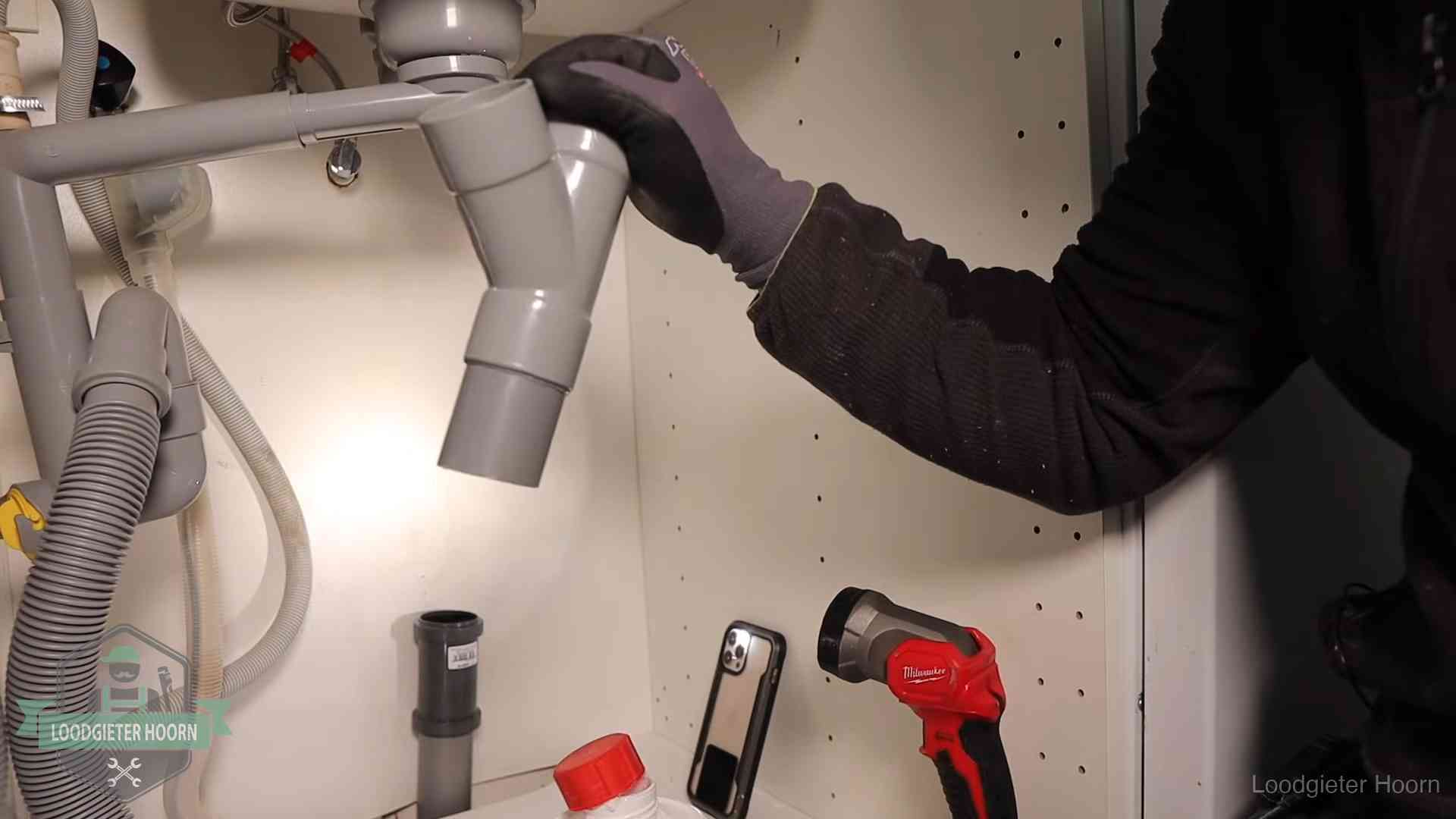 Loodgieter demonteert het sifon- en afvoerwerk onder een gootsteen in Hoorn bij stankklachten