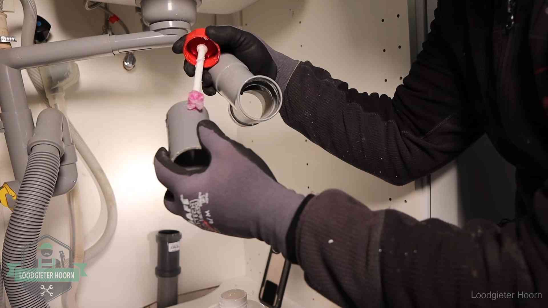Loodgieter demonteert en reinigt de sifon onder een keukenkast in Hoorn