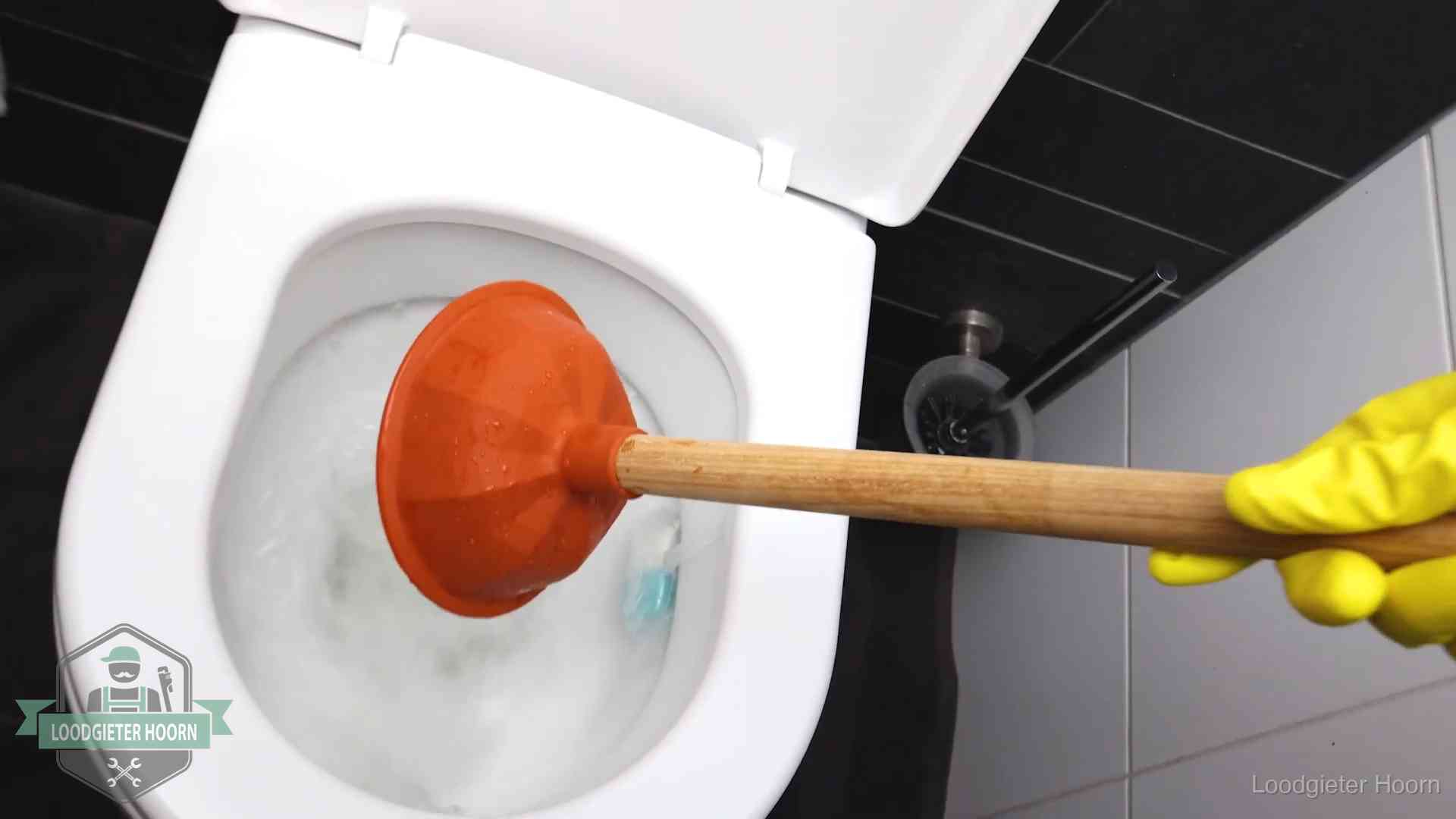 Plopper wordt in de wc-pot gedrukt bij het ontstoppen van een toilet in Hoorn